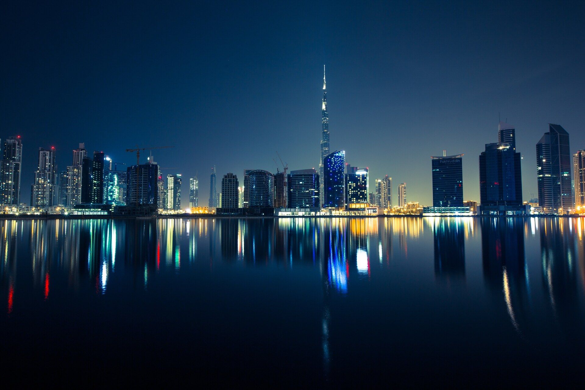 Dubai skyline at night, with the Burj Khalifa reflected in the water